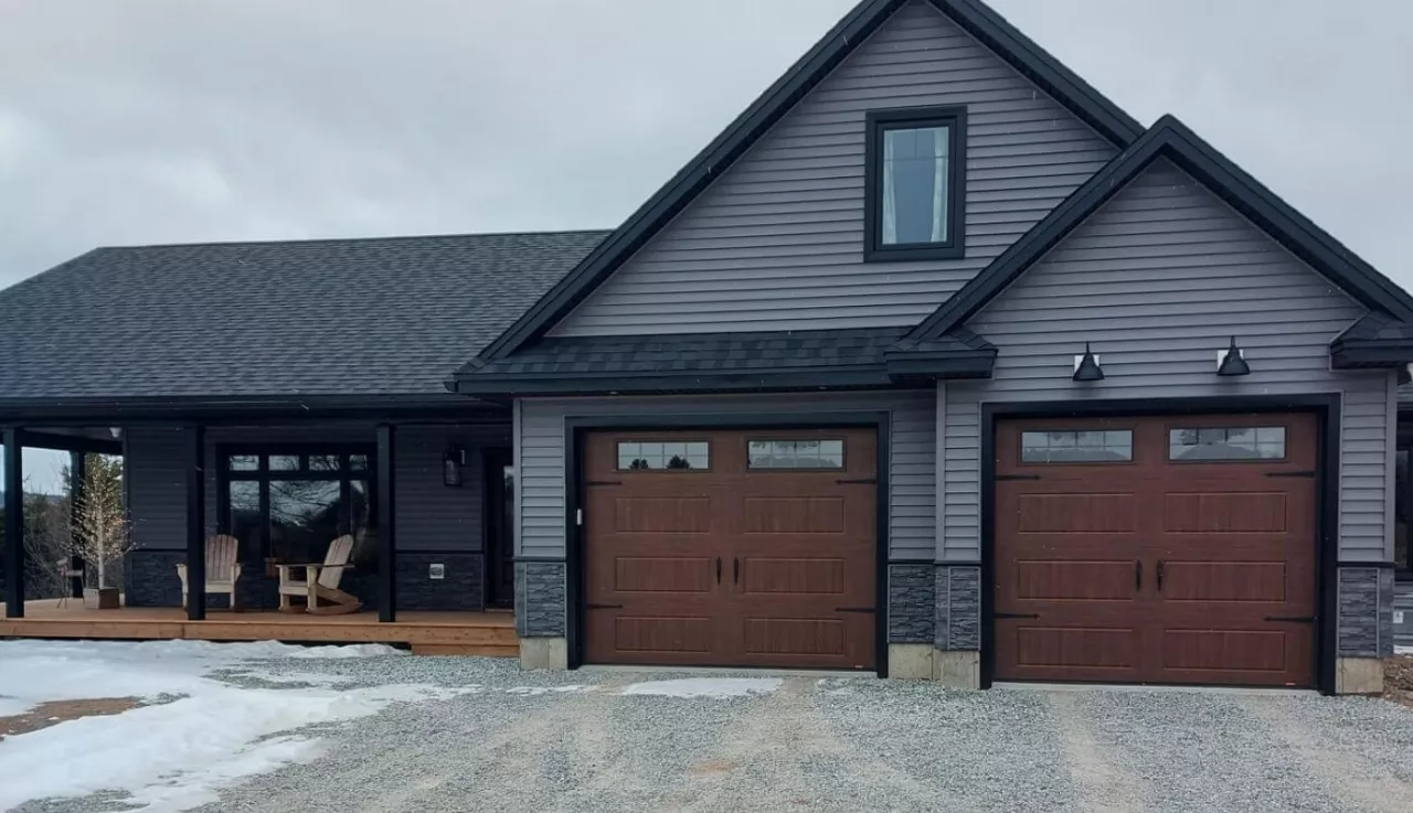 A gray home with two garages and a front porch, showcasing a classic architectural style.